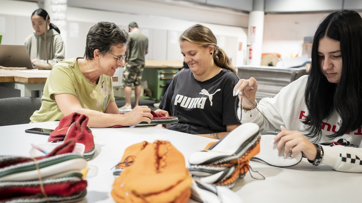 Mitarbeiterin und Kundinnen an einem Arbeitstisch.