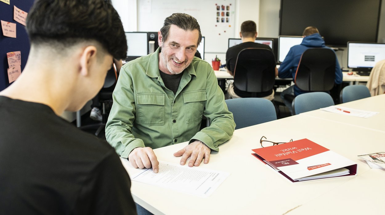 Ein Mann mit einem Jugendlichen bei einem Beratungsgespräch.