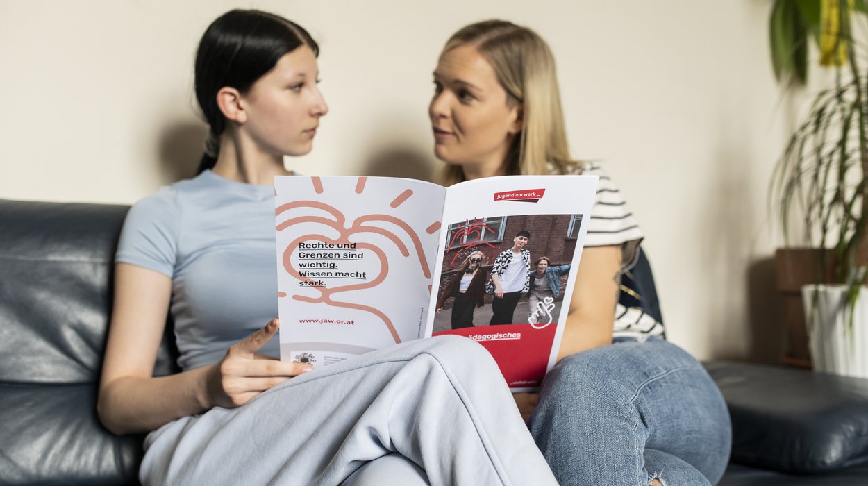 Eine Frau erklärt einem Mädchen etwas in einer Broschüre