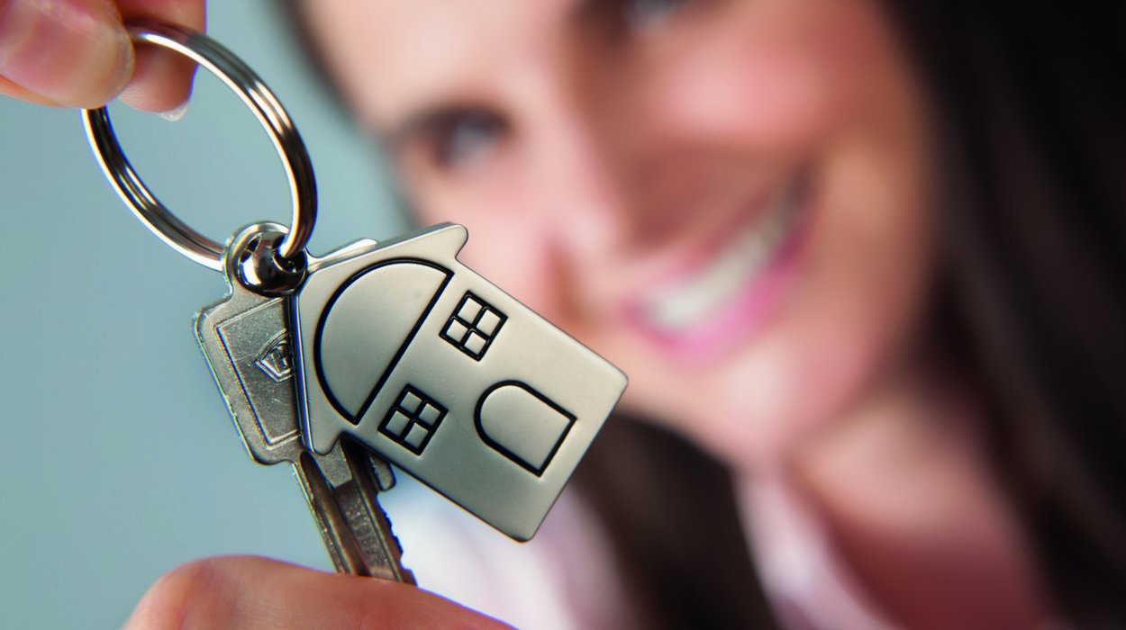 eine Frau hält freudig einen Hausschlüssel