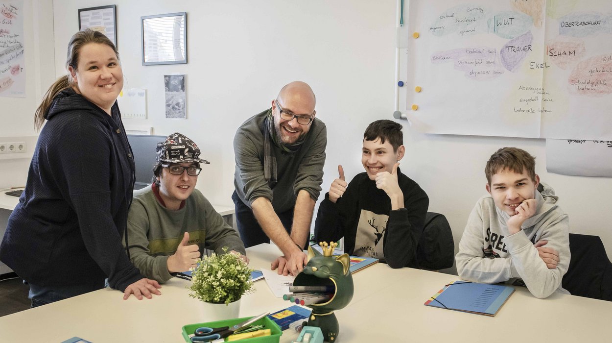 Zentrum-inklusiver-Arbeitsmarkt_Guertelturm_Jugend-am-Werk-Steiermark Vier Jugendliche mit Behinderung mit einem Lehrer an einem Tisch