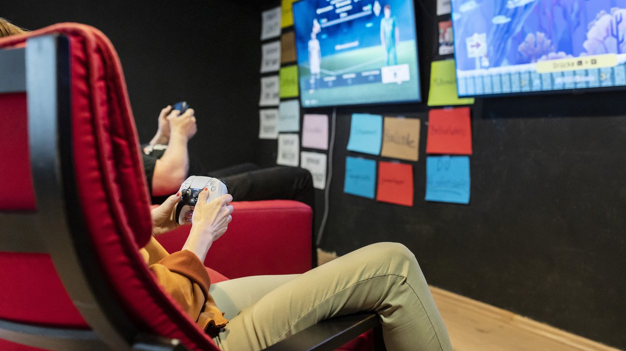 zwei Jugendliche gamen nebeneinander in einem coolen Raum