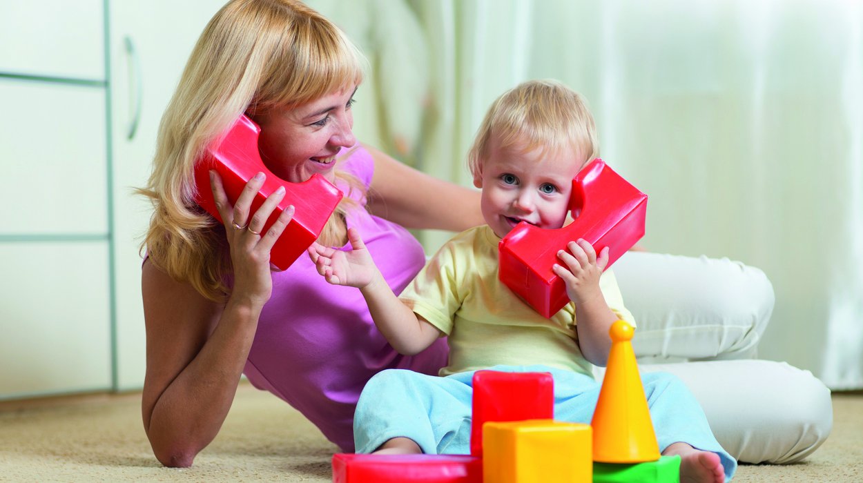 Fruefoerderung_Jugend-am-Werk-Steiermark eine Frau spielt mit einem kleinen Kind mit Bauklötzen