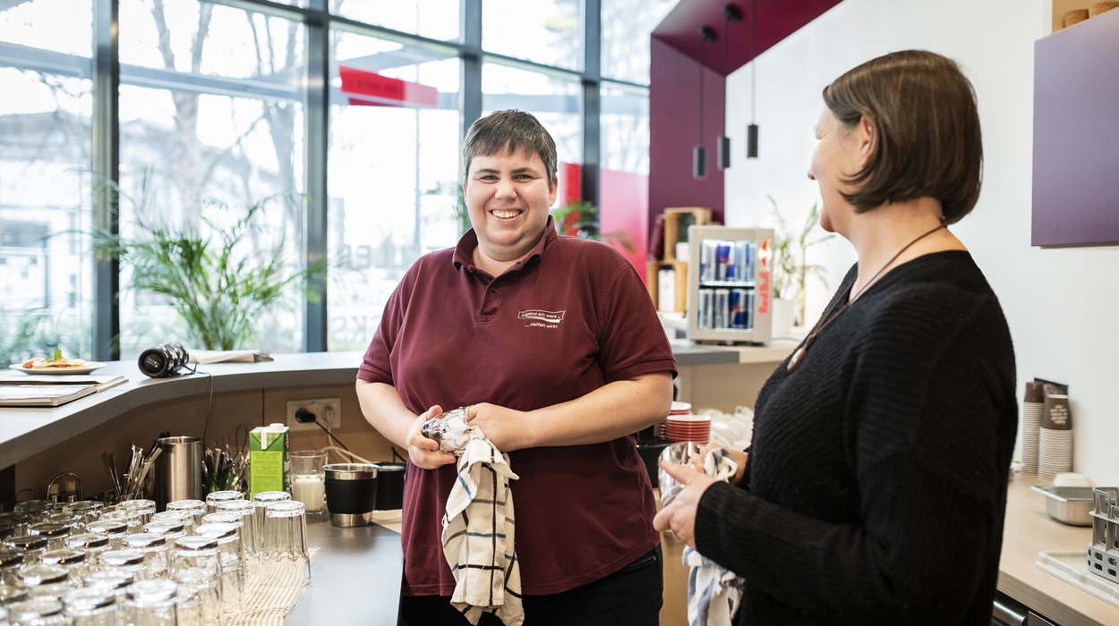Eine Frau mit Behinderung trocknet ein Glas ab.