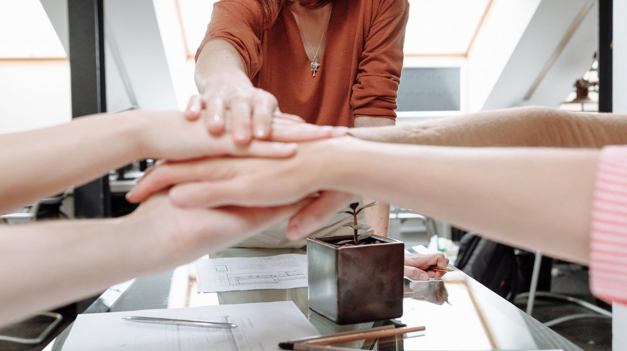 mehrere Personen halten ihre Hände aufeinander