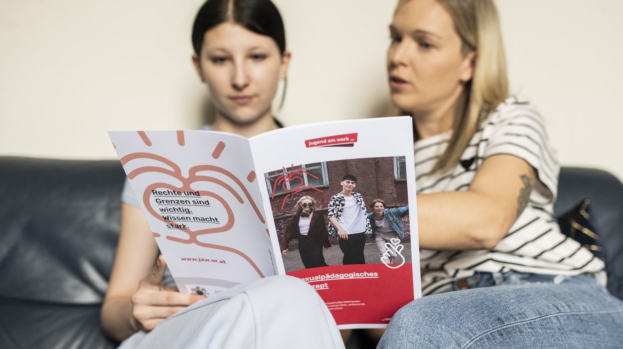 Betreuerin berät eine Jugendliche, beide sitzen auf der Couch