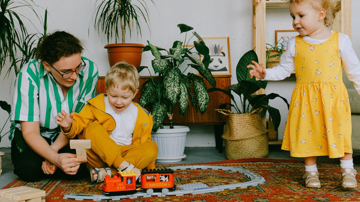 eine Frau spielt mit zwei jungen Kindern in einem Raum mit guter Atmosphäre