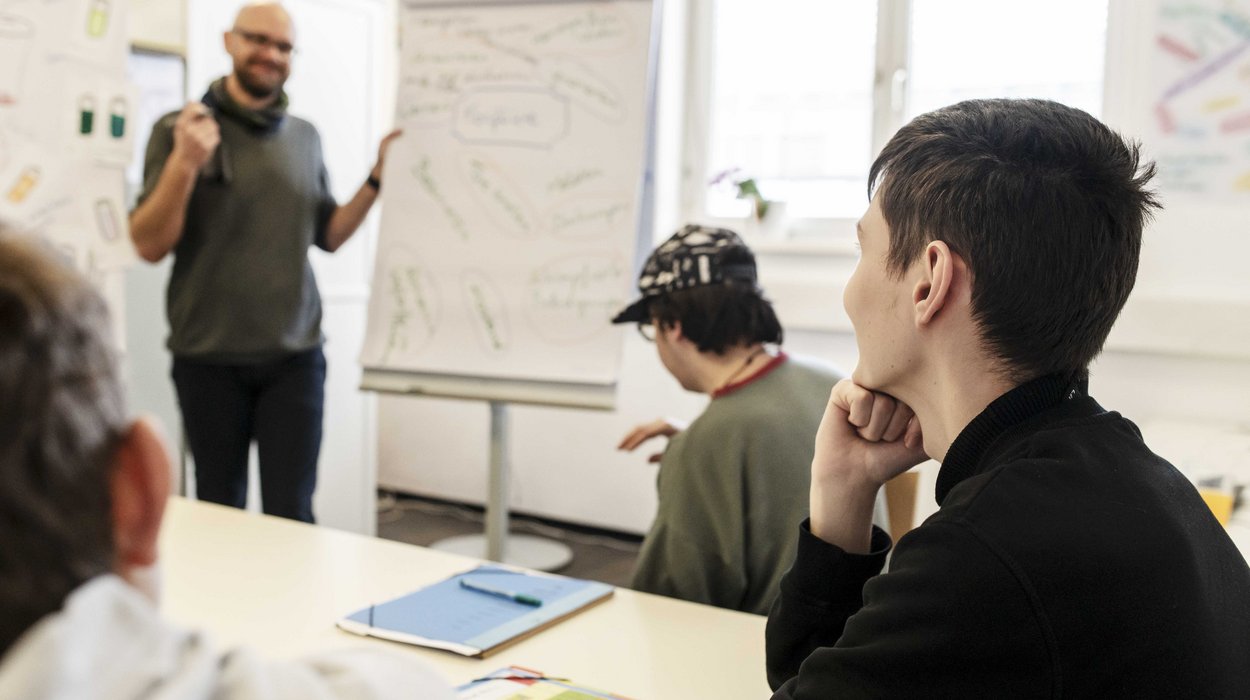 MyLife bietet beste Startbedingungen für Jugendliche auf dem Weg ins Arbeitsleben drei Jugendliche hören einem Ausbilder zu, der Dinge am Flipchart erklärt