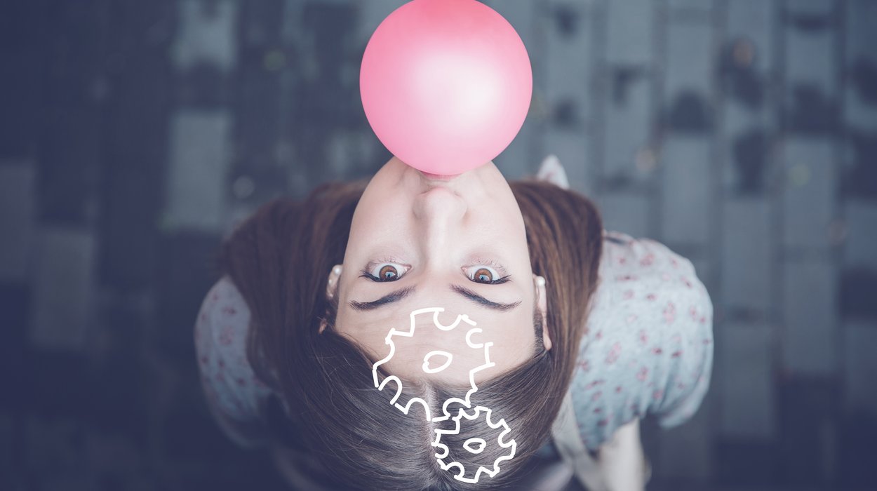 Eine junge Frau die nach oben schaut und eine Kaugummiblase macht