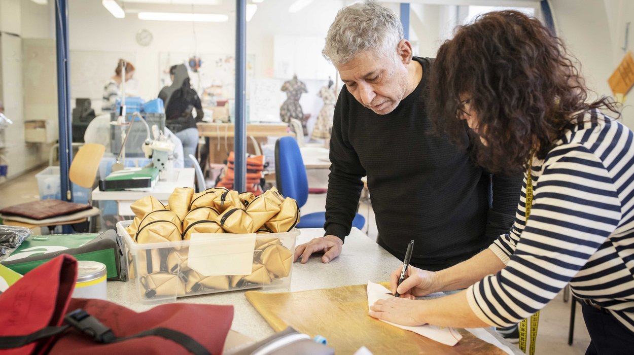Naehwerkstatt_Jugend-am-Werk-Steiermark Ein Mann und eine Arbeitsanleiterin an einem Tisch mit verschiedenen Stoffen in der Nähwerkstatt.