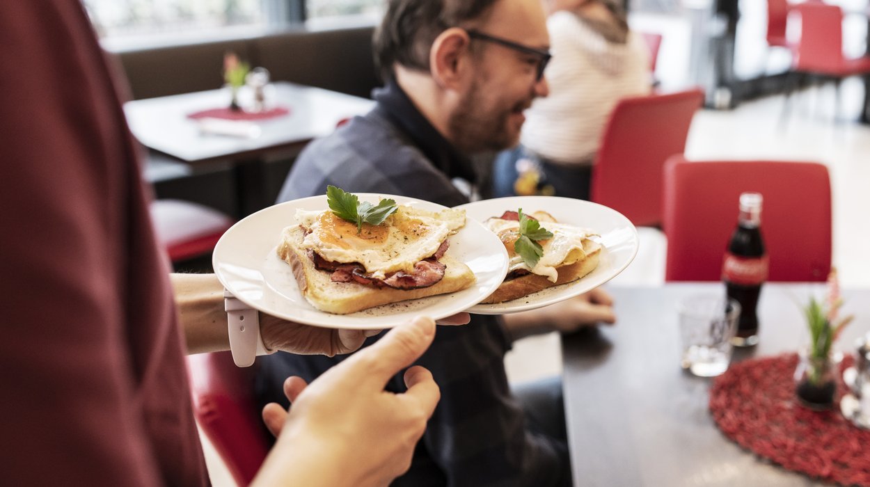 Speisen werden zu einem Gast an den Tisch gebracht.