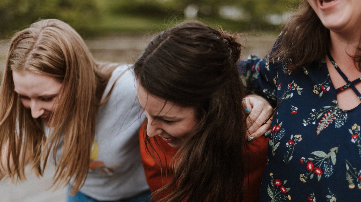 drei Frauen halten an sich gegenseitig mit ihren Armen und haben Spaß