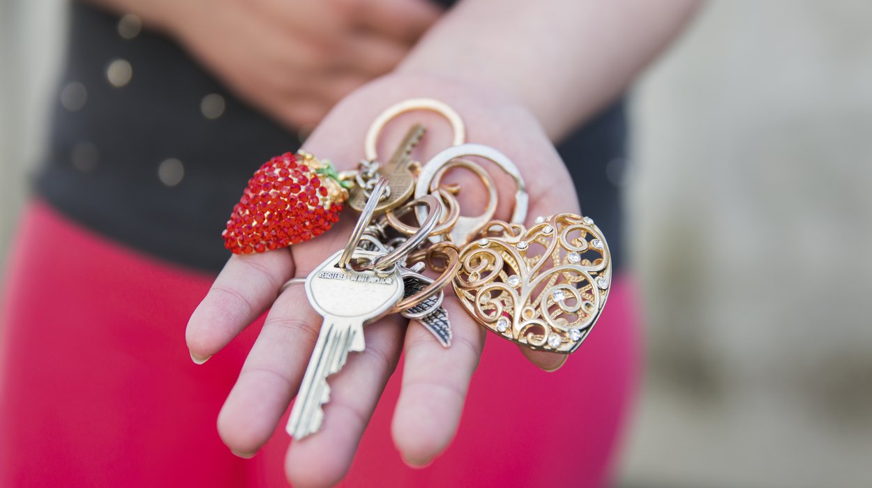 Betreutes-Wohnen_Jugend-am-Werk-Steiermark eine Hand mit einem goldenen Schlüsselbund mit mehreren Schlüsseln und funkelnden Anhängern