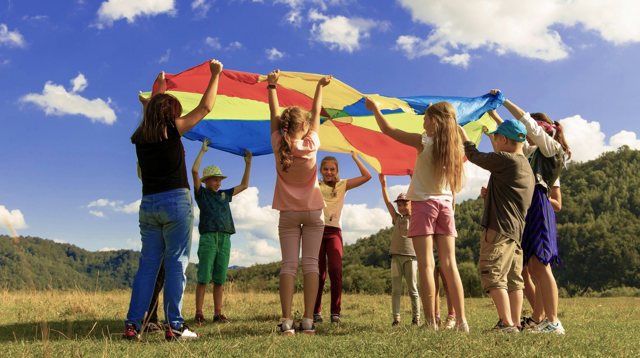 Wohnen-fuer-Kinder-und-Jugendliche_Jugend-am-Werk-Steiermark Kindergruppe spielt draußen mit einem Schwungtuch